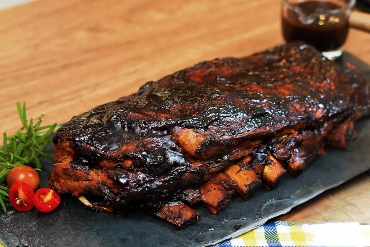 Costelinha de porco assada com molho barbecue que sai forno soltando do osso